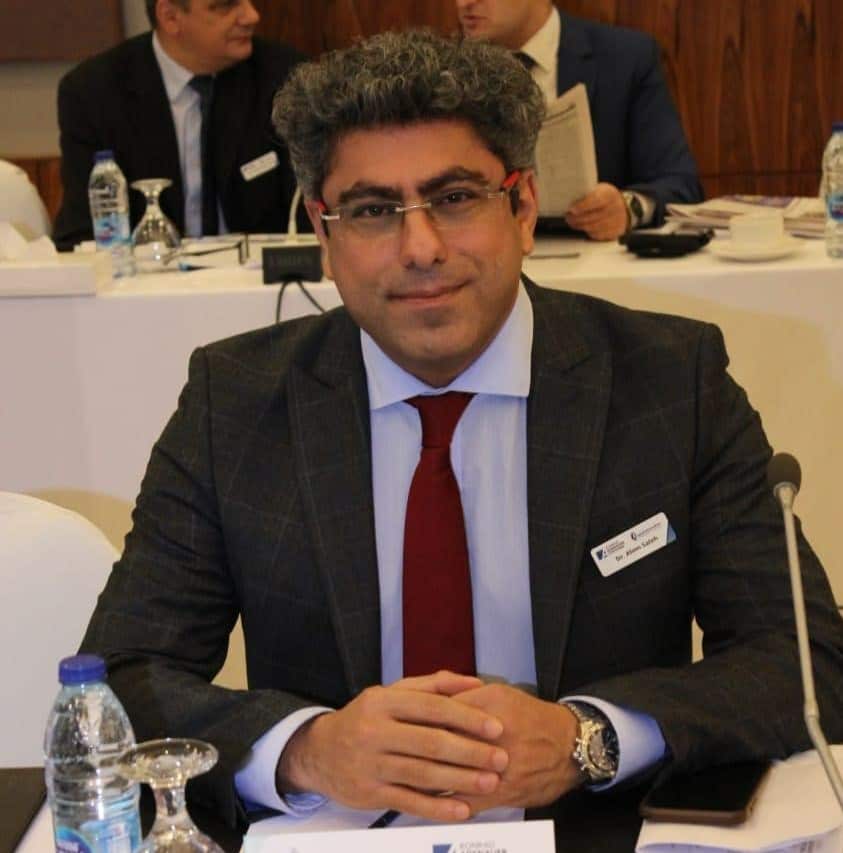 A man in a suit sitting at a table in a conference room