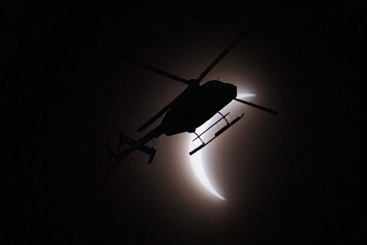 A helicopter flies across the sky during a solar eclipse