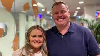 A close-up photo of a young blonde woman and a man in an office