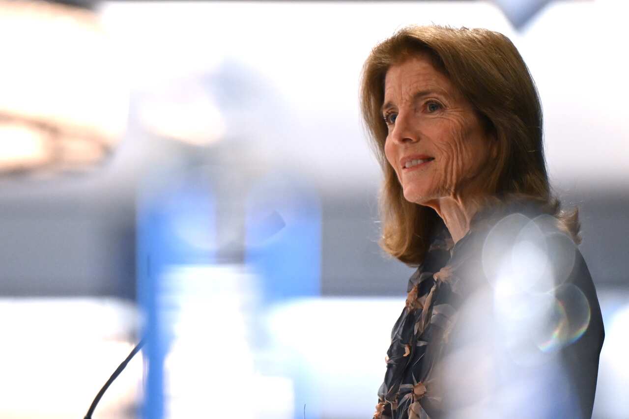 A side profile of a woman speaking while standing at a lectern.