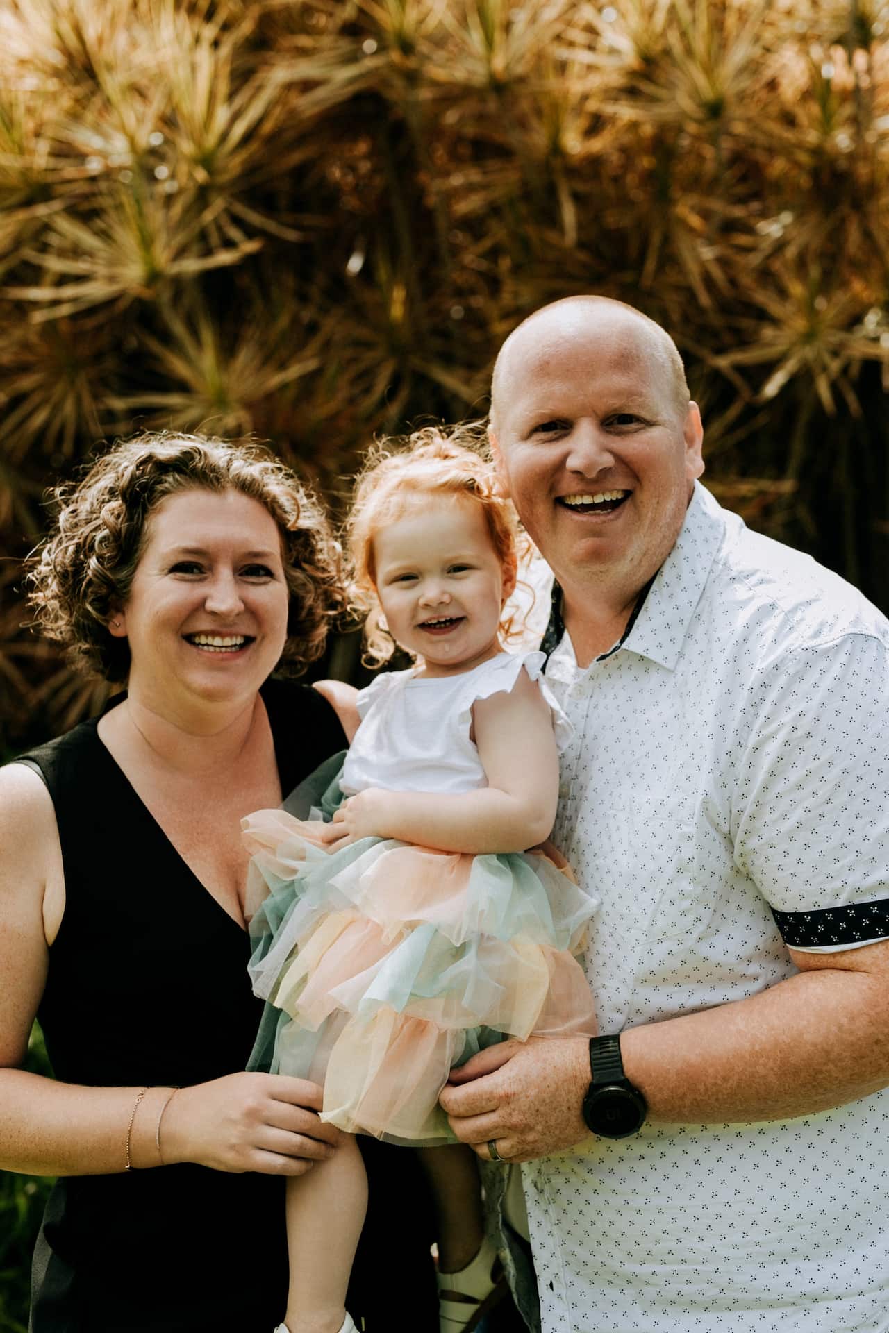 Woman and man smile at the camera while holding child