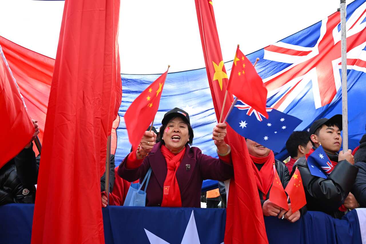 A group of people waving Chinese and Australian flags.