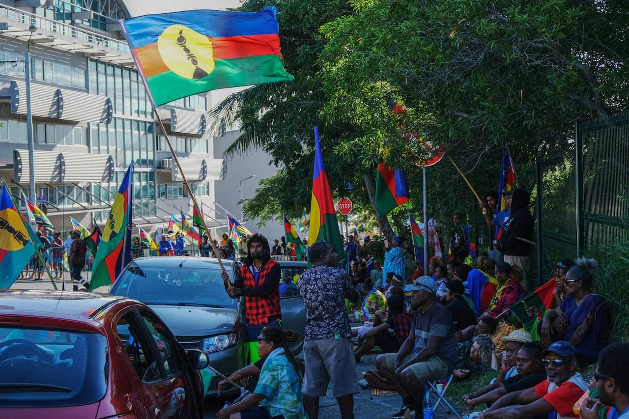 Many protesters march the streets of Noumea with flags held high.