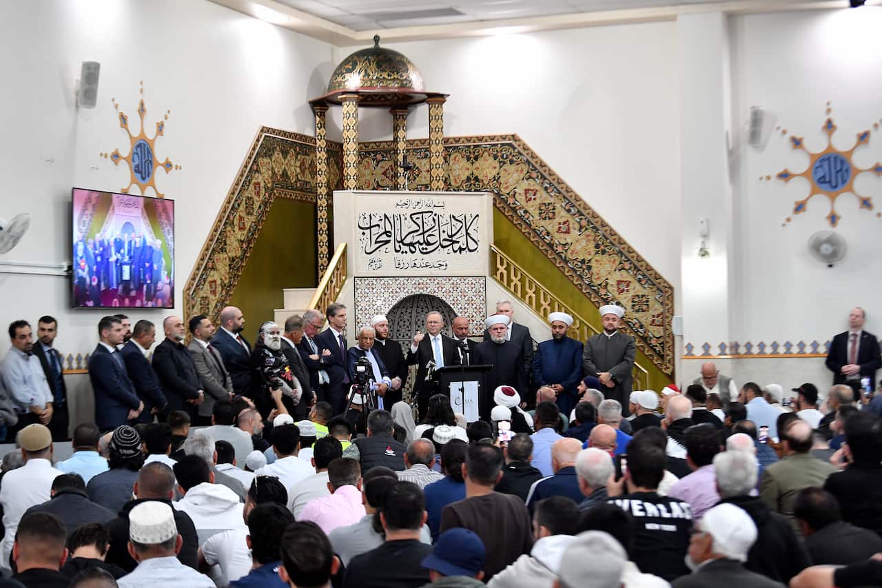 ANTHONY ALBANESE stands in front of dozens of muslim men inside mosque.