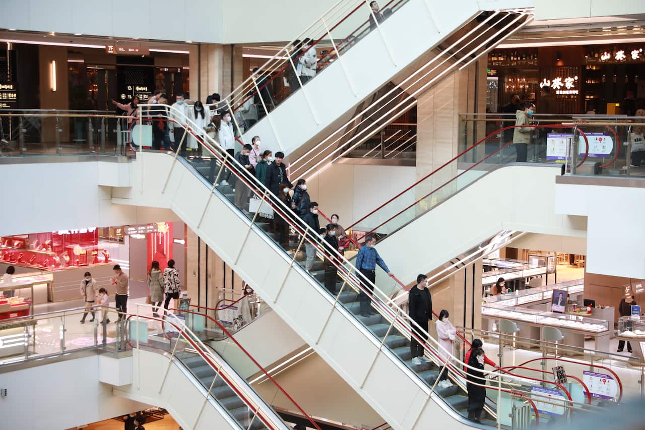 People waring masks standing on an escalator in a shopping mall in Xi 'an, Shaanxi province, China.