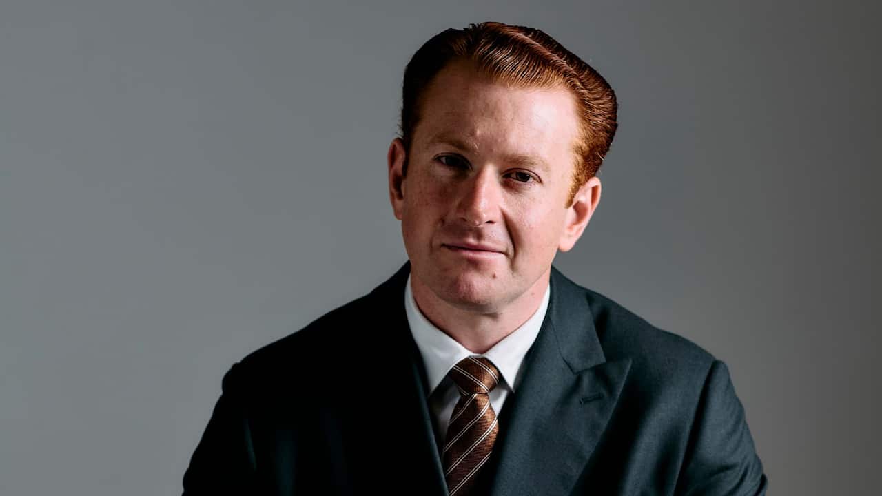 A close-up shot of a red haired man in a suit and tie