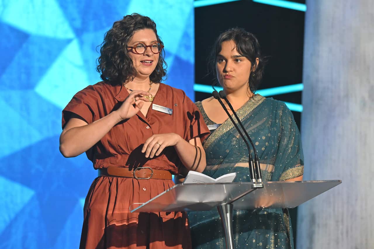 Two women stand behind a lectern microphone.