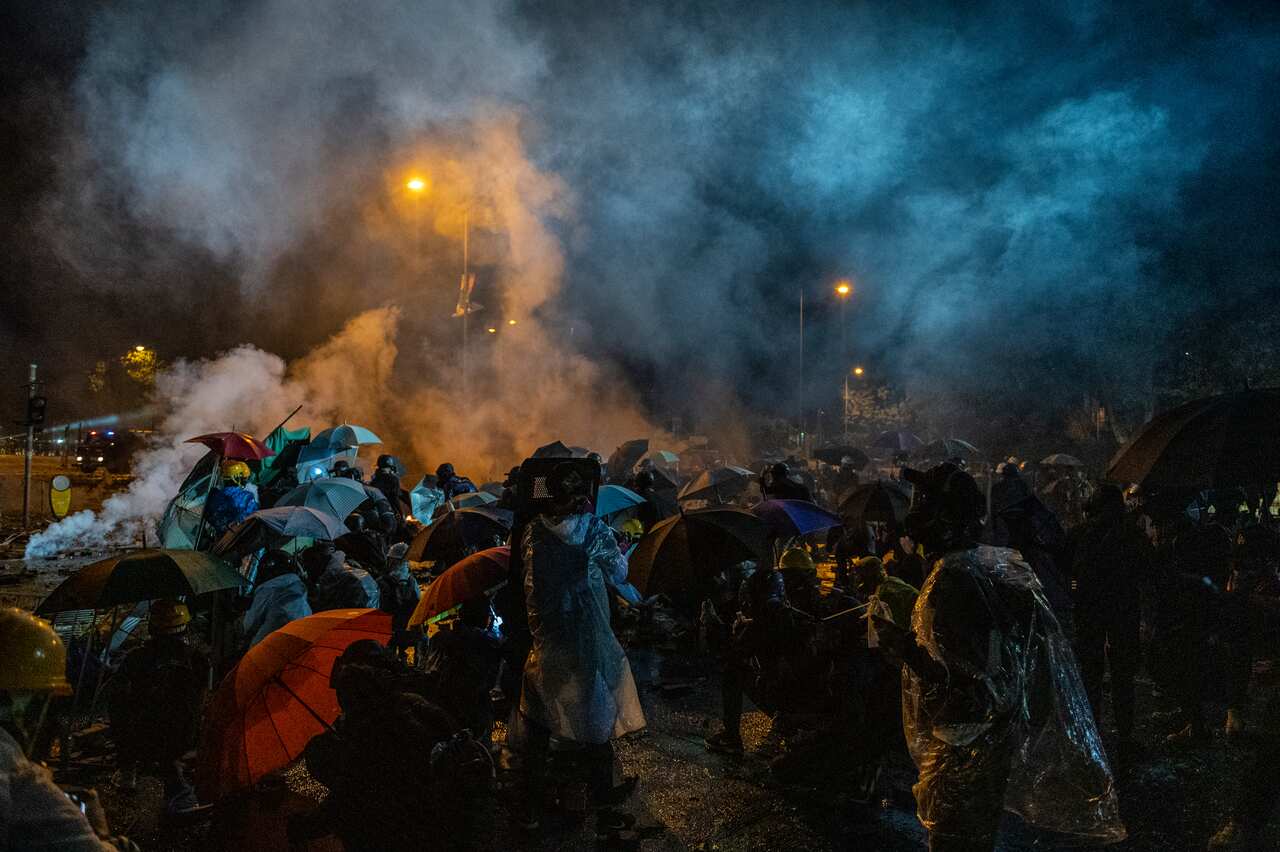 Protesters stand inside a cloud of tear gas smoke. 