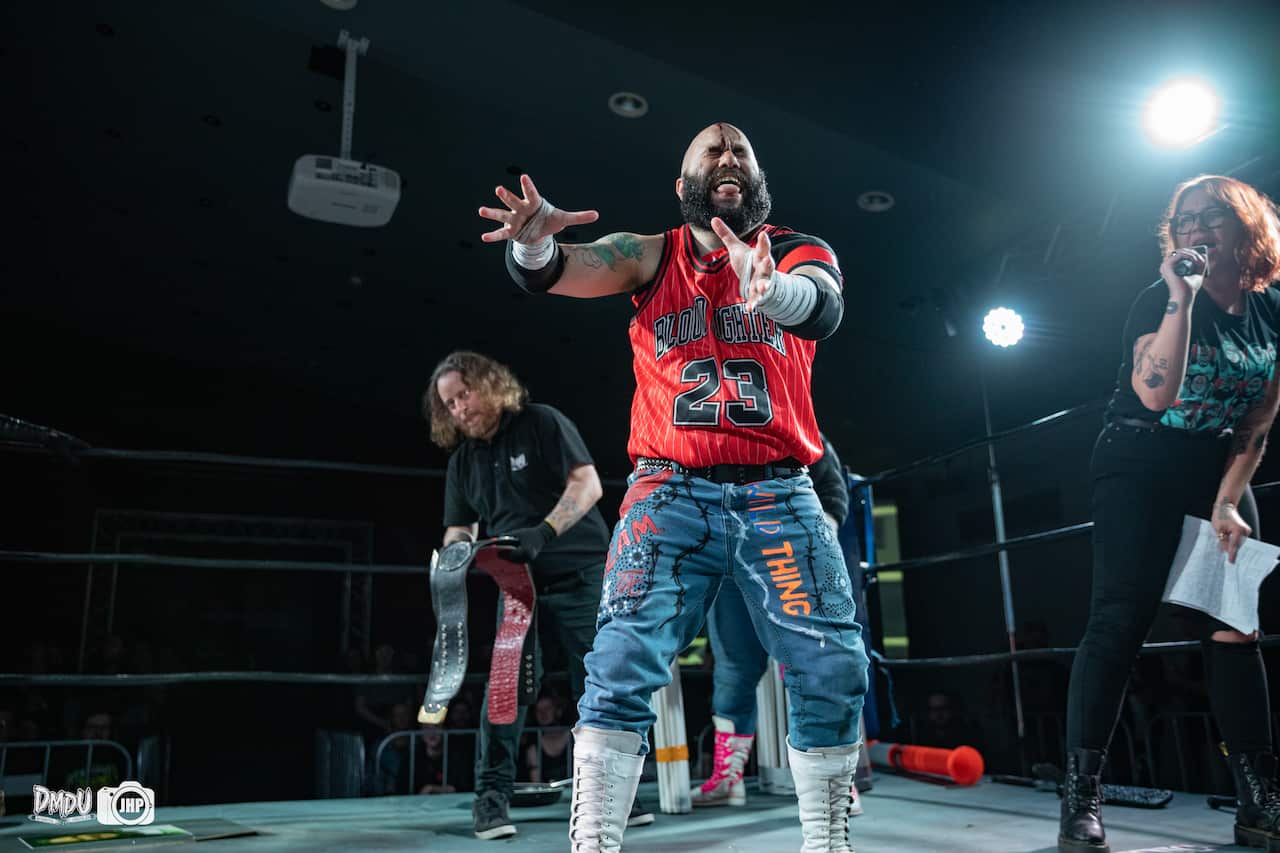 A wrestler in a ring with an announcer and referee. 