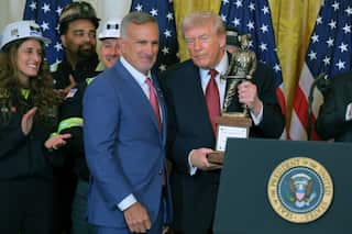 A photo of US President Donal Trump receiving a bronze statue of a coal miner at the White House.