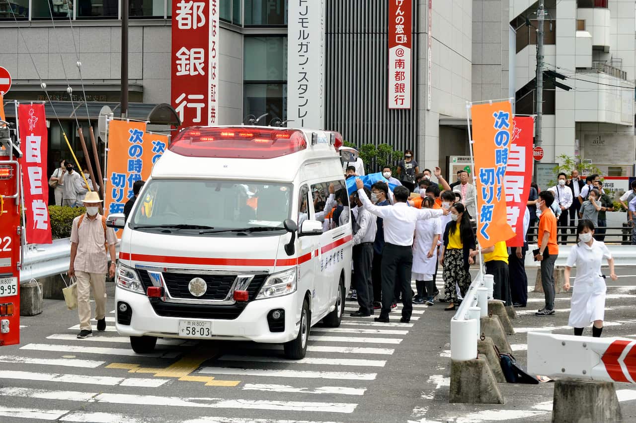 People crowded around an ambulance in a city.