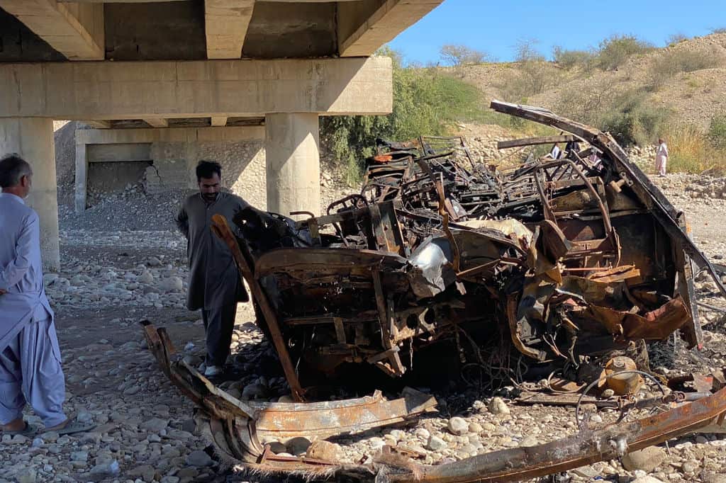 Residents look at the wreckage of a burnt passenger bus in Lasbela district of Pakistan's Balochistan province.