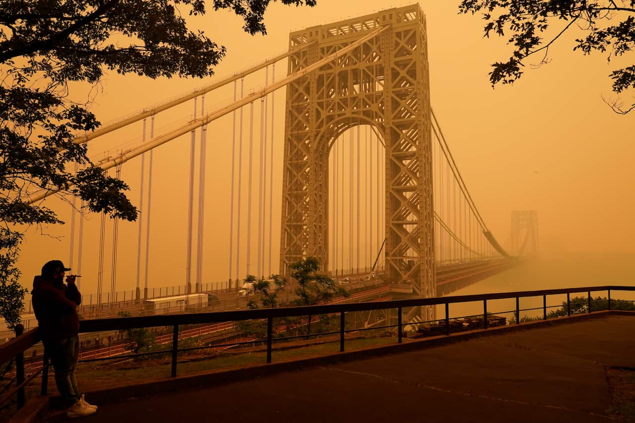 A view of a city bridge surrounded by an orange mist. 