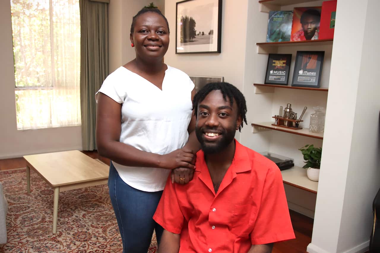 A woman in a white top and a man in a red shirt smile