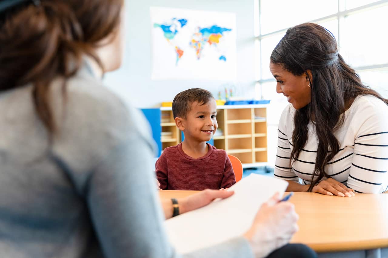 A child next to their mum sitting across from a health professional.