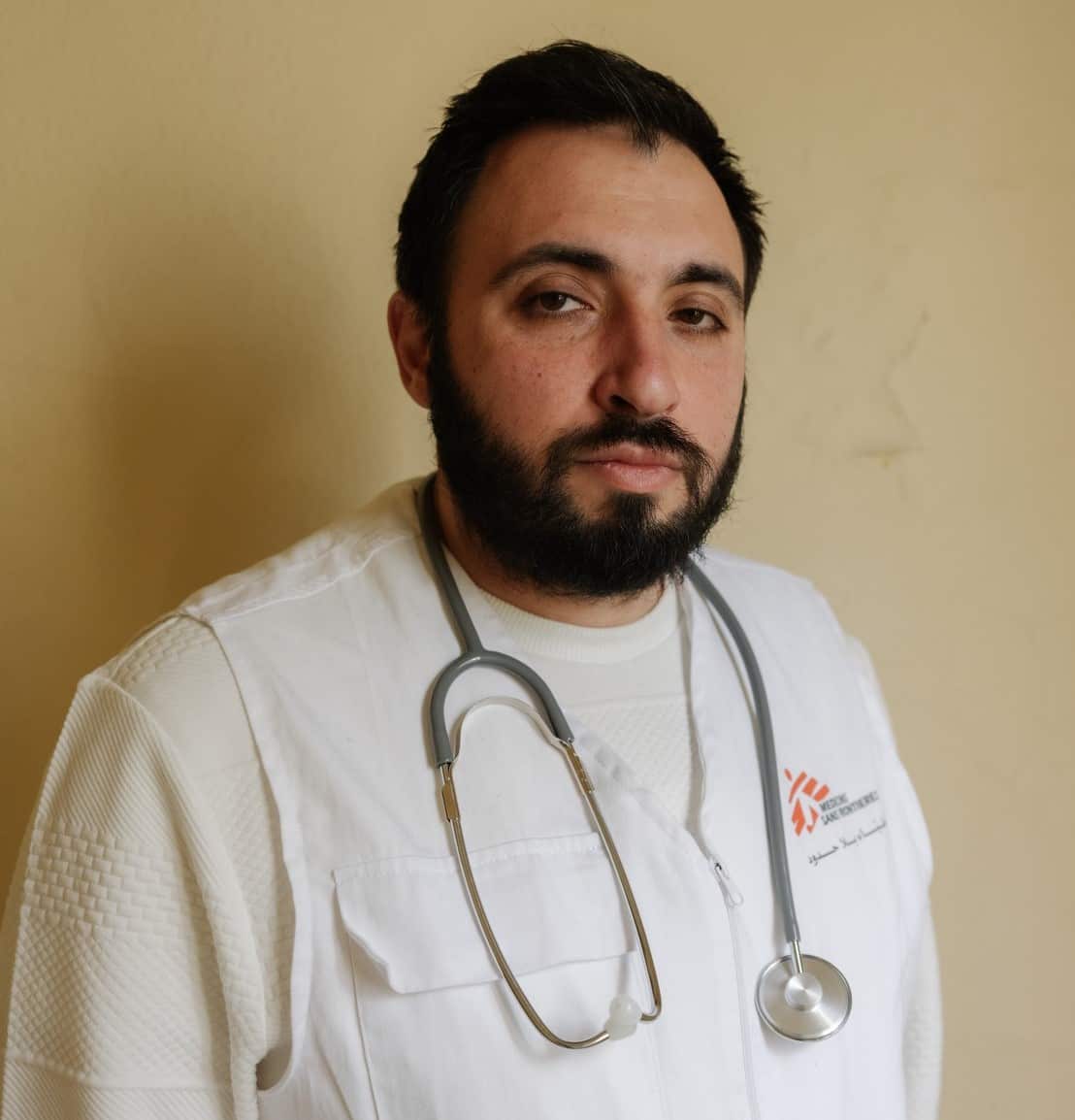 A side profile of a man in a white lab coat and a stethoscope around his neck.