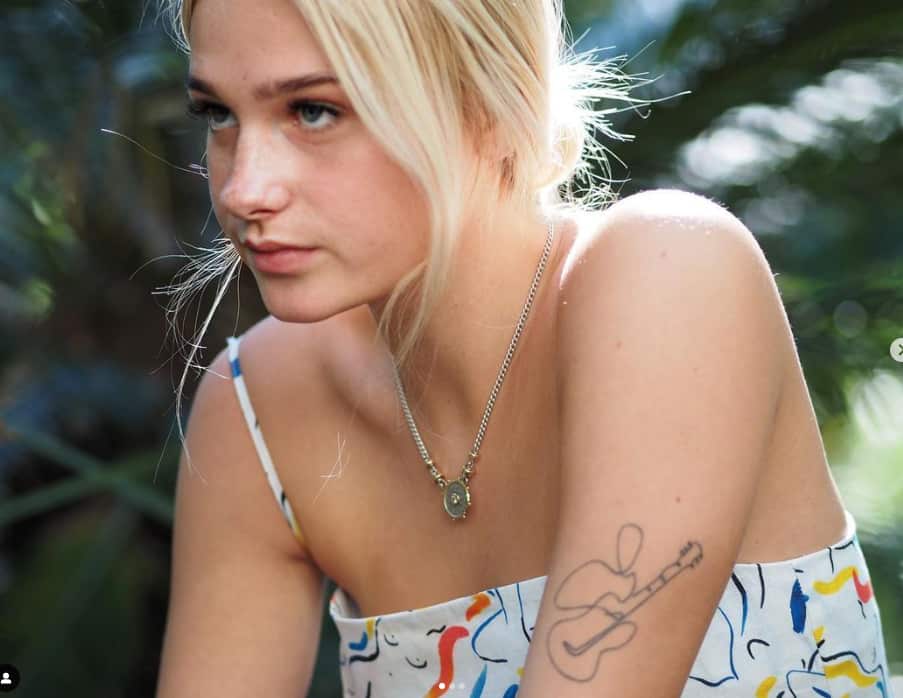 A close-up image of a teenage woman with blonde hair with a serious expression on her face. 