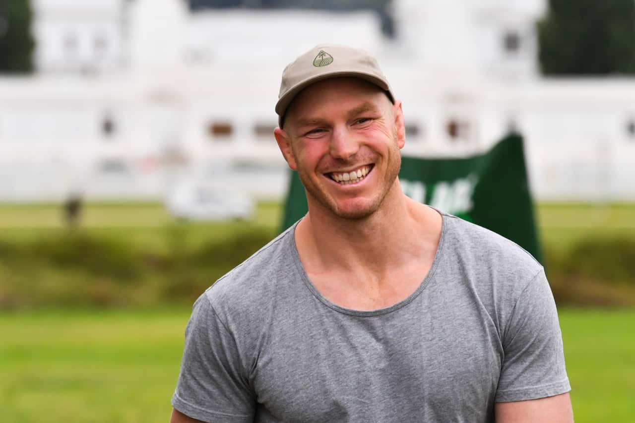 A smiling Senator-elect David Pocock in a park wearing a T-shirt and cap.