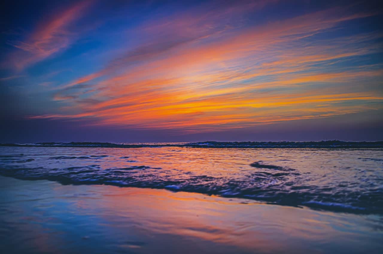 A dramatic cloud formation and deep vibrant colours formed during sunset at a beach near Surat, Gujarat, India.
