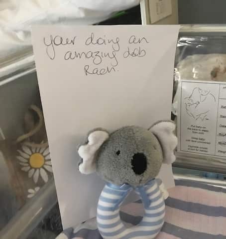 A note reading 'You're doing an amazing job Rach' with a baby toy attached.