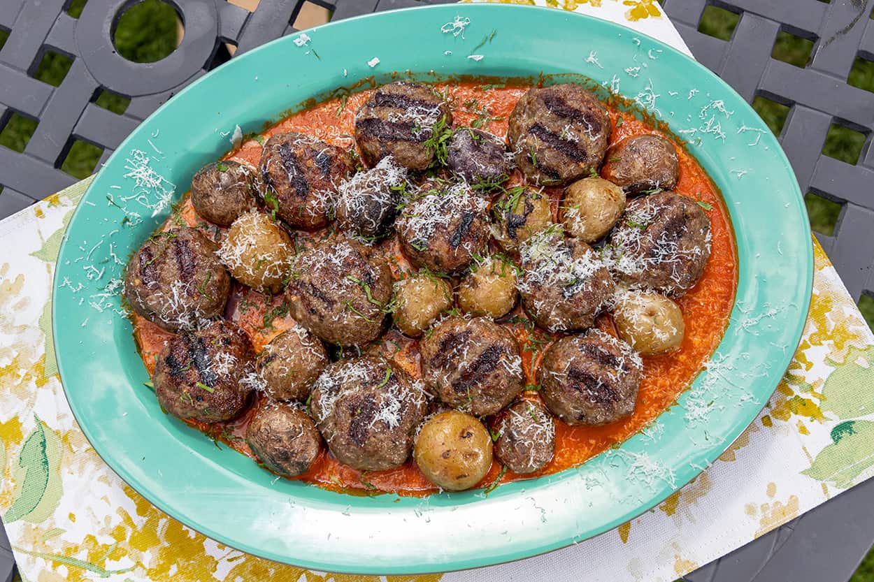 An oval green dish sits on a patterned tablecloth. The dishholds 