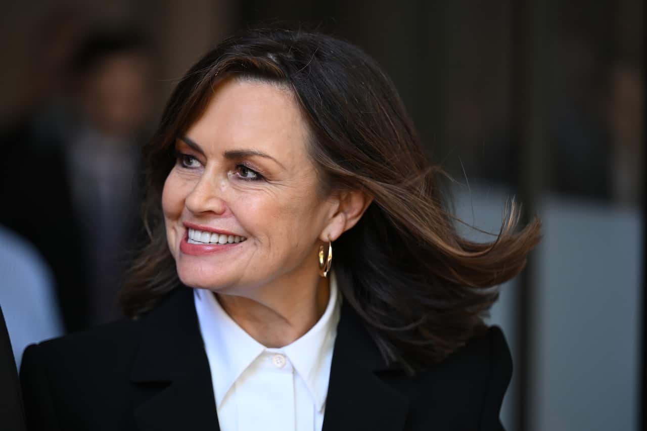 A woman wearing formal attire speaks as she walks.