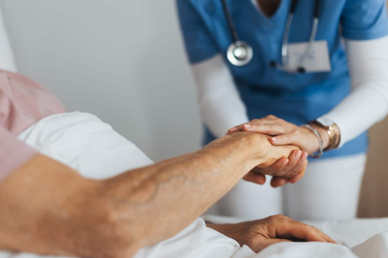 Close-up of caregiver holding senior client hand