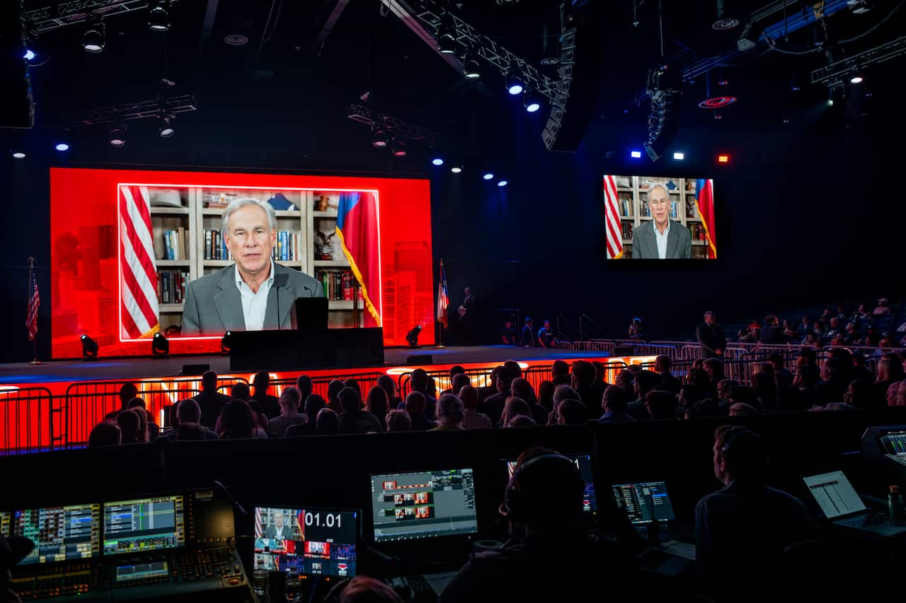 People watching a man speaking on a screen.