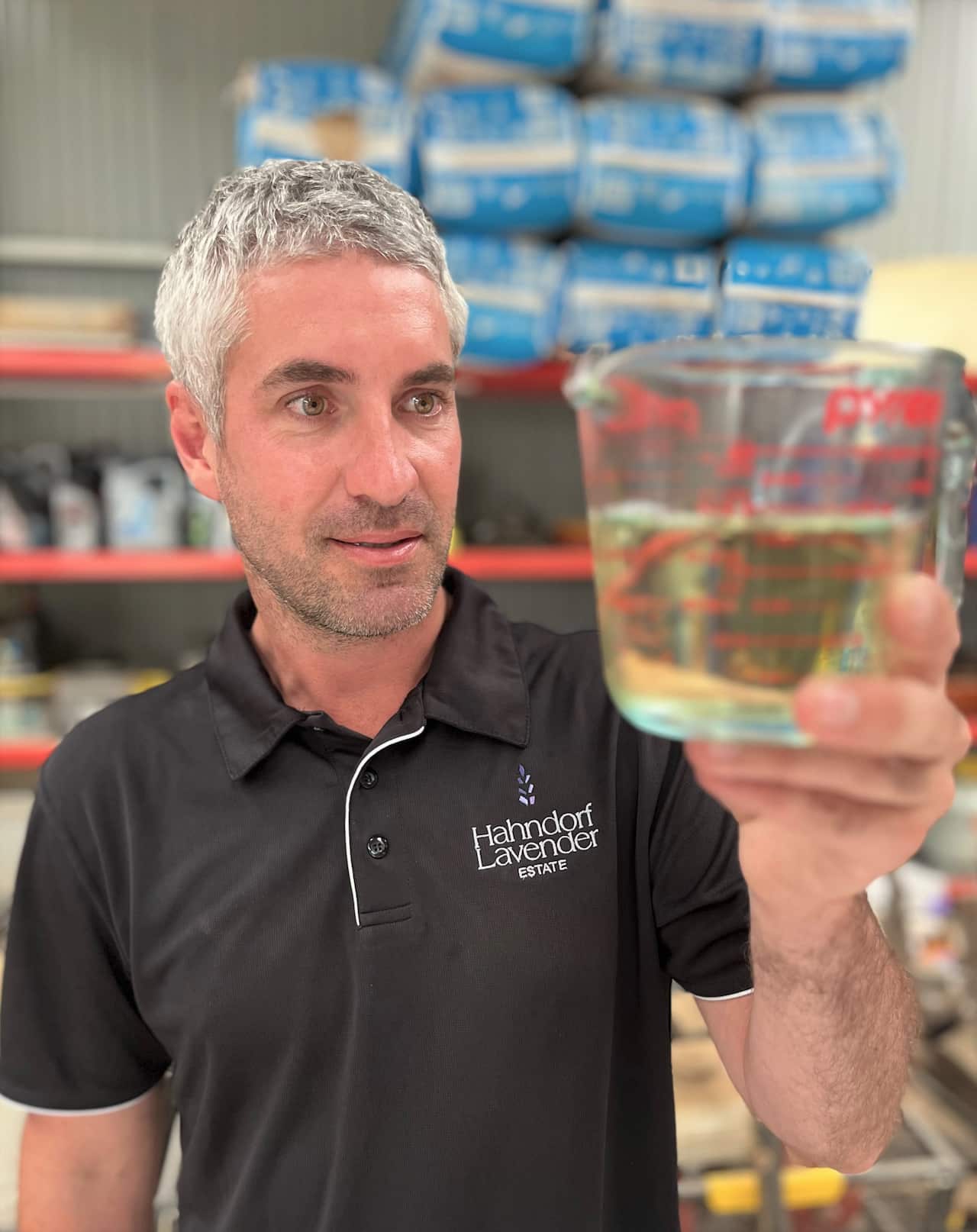 Thomas Mahar golds a glass beaker of extracted lavender oil.