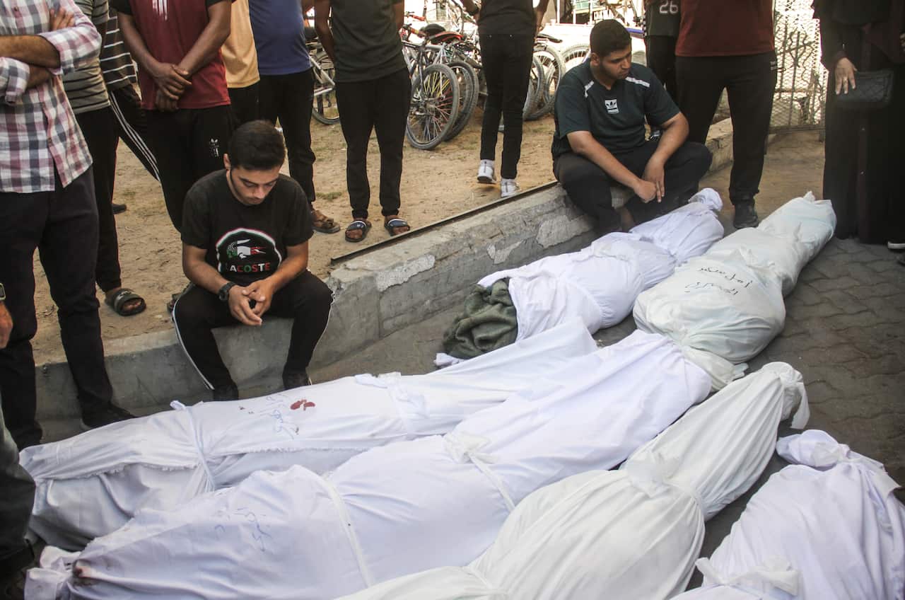 Men look down on bodies shrouded in white cloth