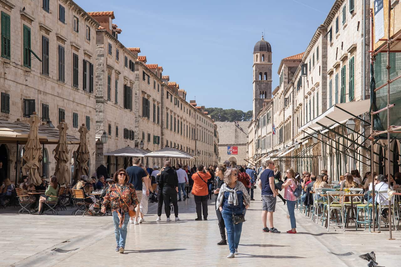 People walk down a street in a historic area