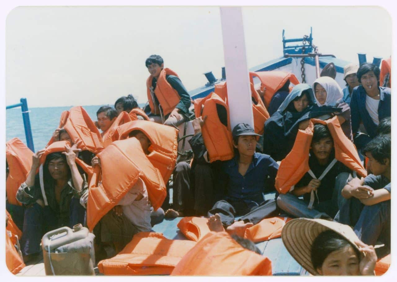 Vietnamese refugees on a boat carrying life jackets, being transported to a refugee camp.