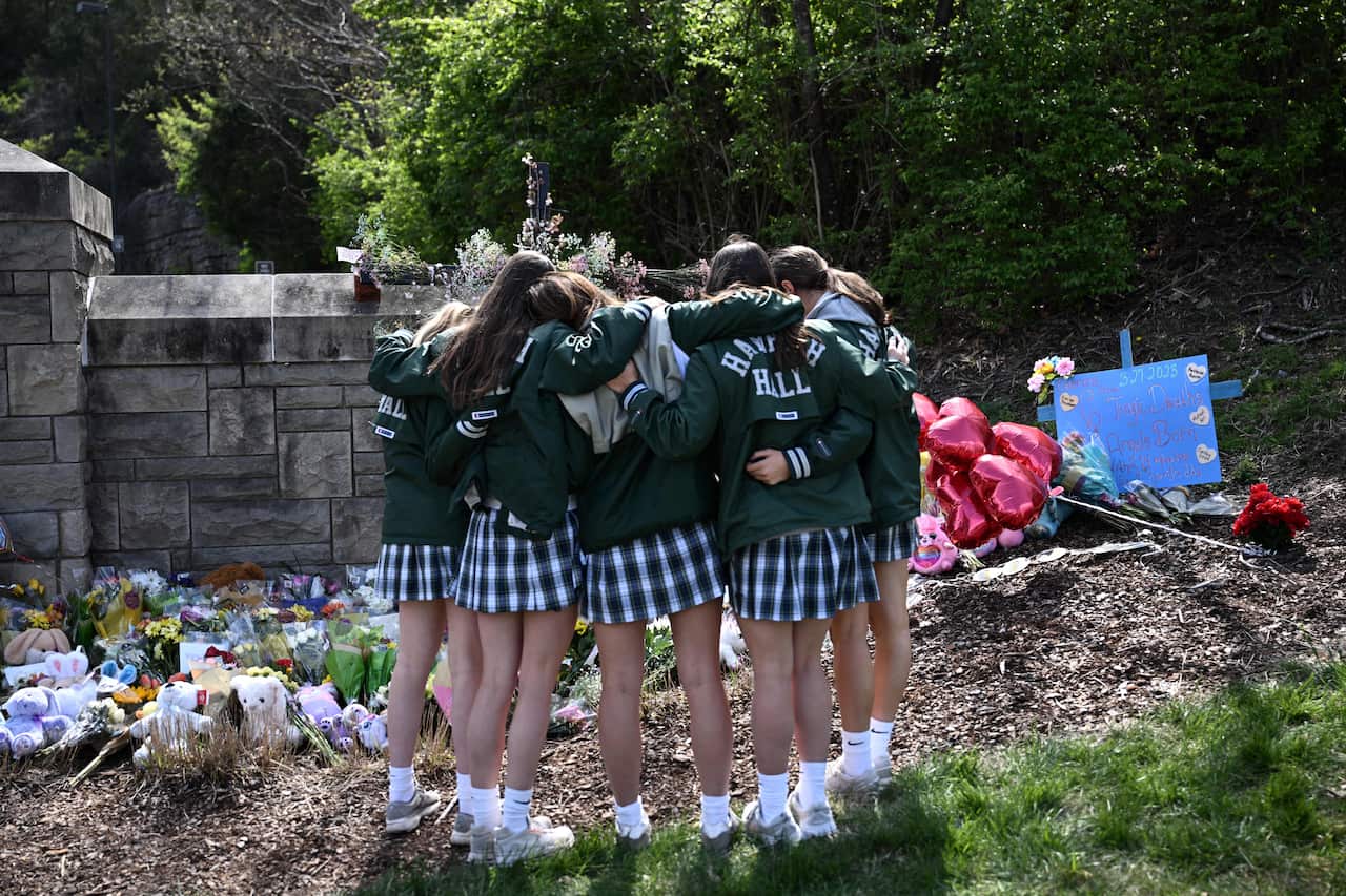 School girls embrace in front of a makeshift memorial for victims by the Covenant School building at the Covenant Presbyterian Church following a shooting, in Nashville, Tennessee.