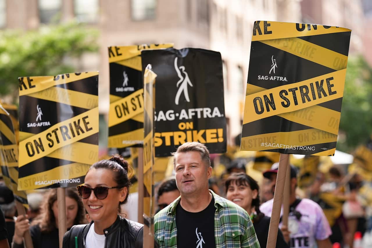 People standing outside holding signs that say "SAG-AFTRA ON STRIKE!".