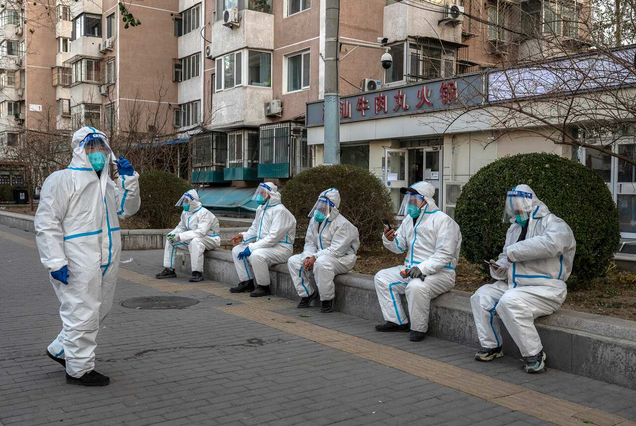 People wearing personal protective equipment outside an apartment building.