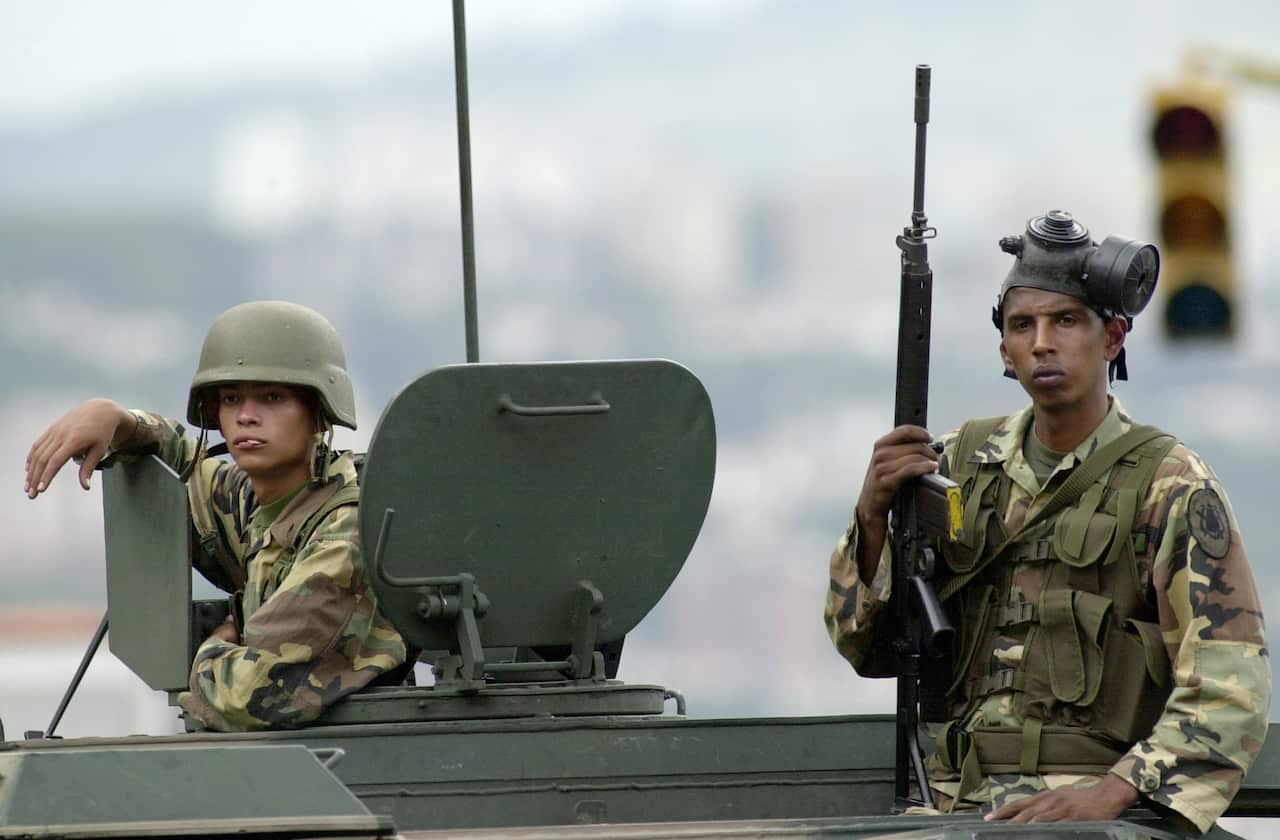 Two Venezuelan army soldiers guard on an armored tank out side of a police station in Caracas, Venezuela