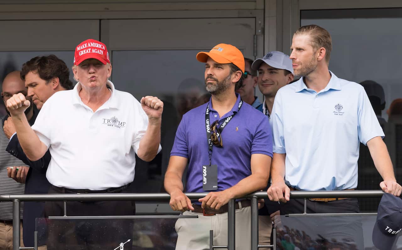 Three men watching a game of golf