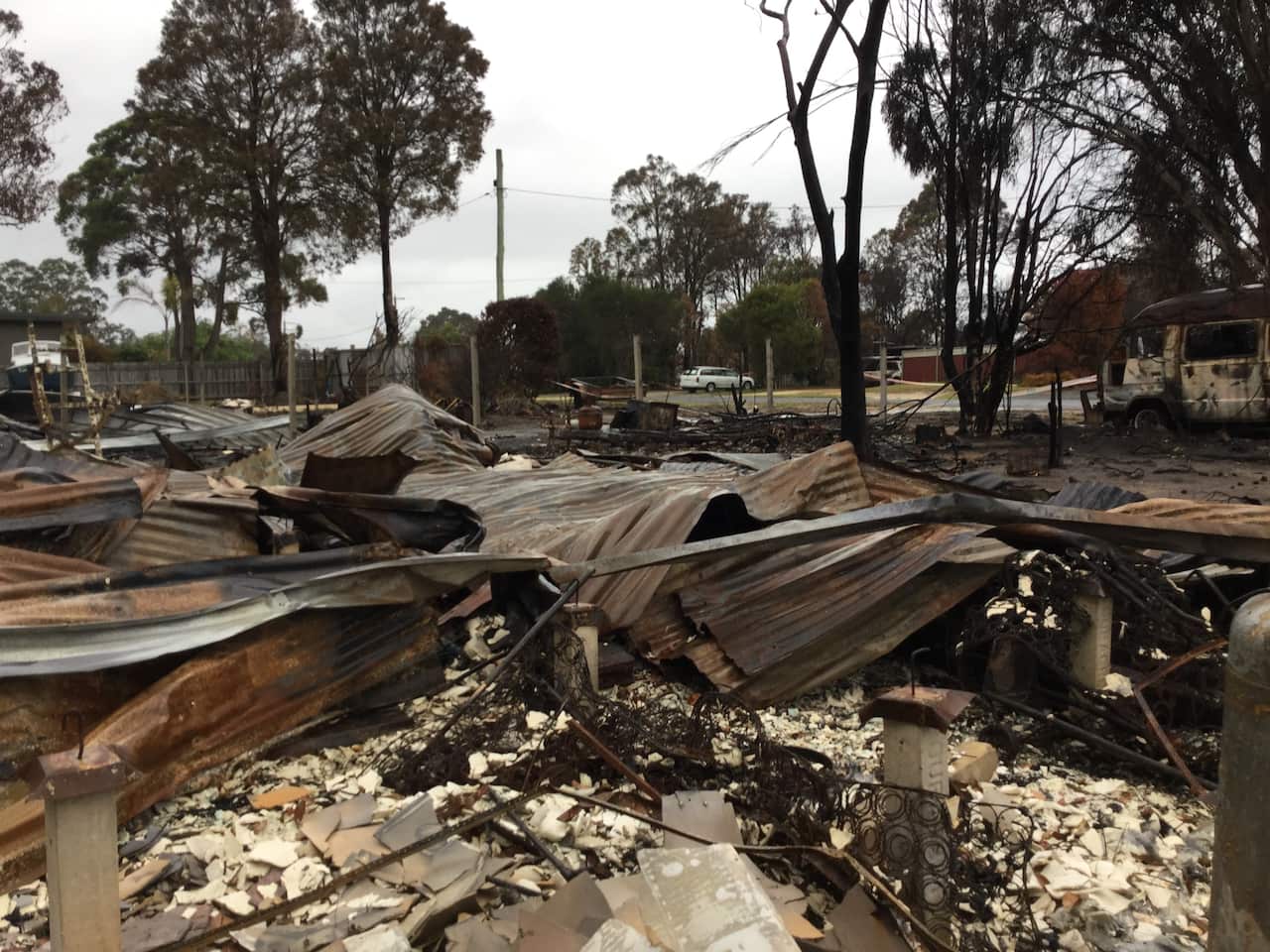 A house flattened and blackened by a bushfire.