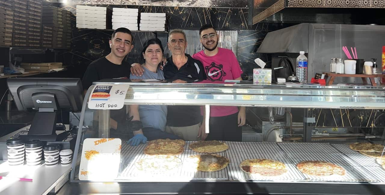 A family of four people are hugging each other, smiling, at a cafe.