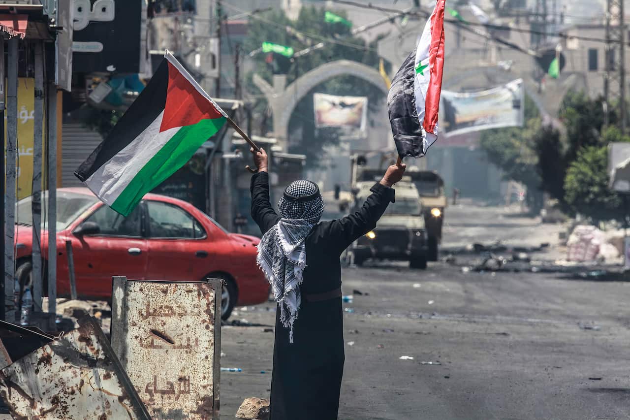 A person stands with flags in this hands.