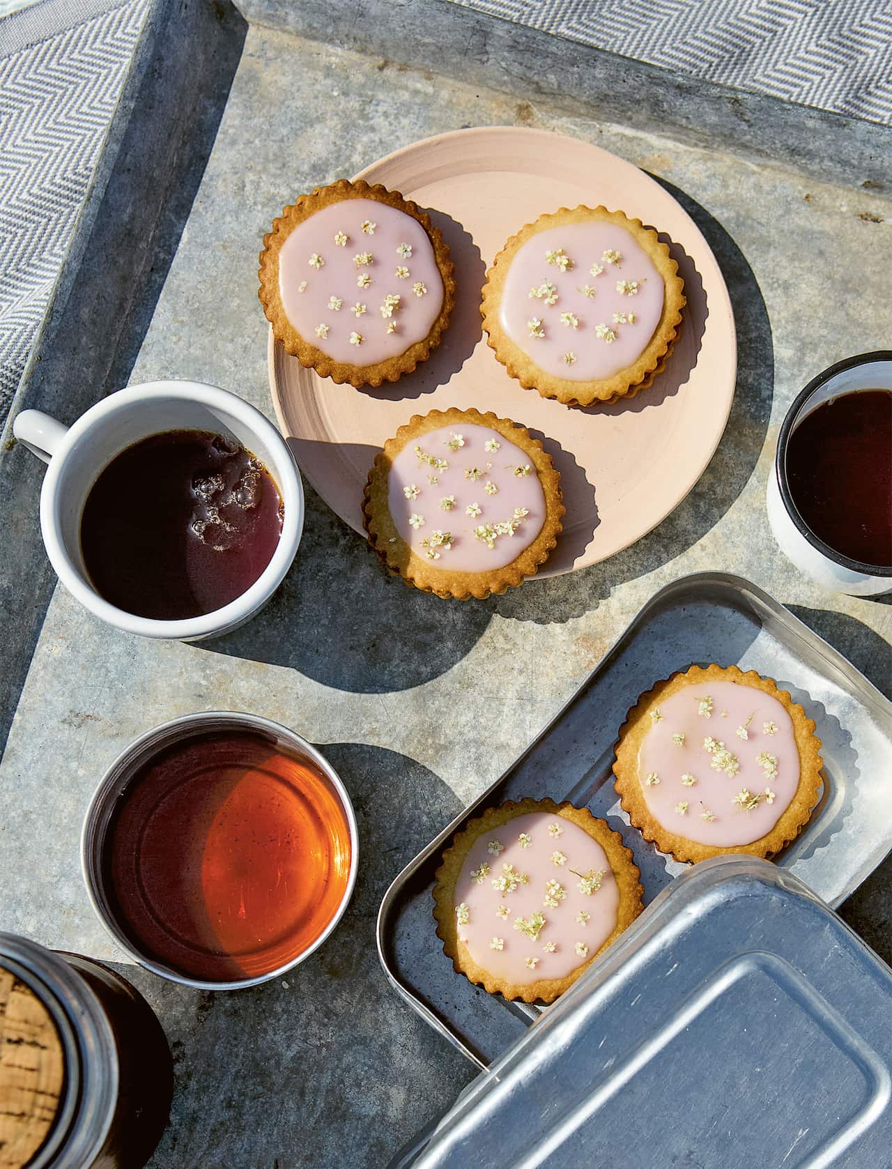 Three small round cakes with pink icing sit on a plate.