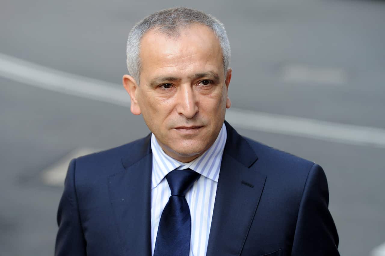 A man in a dark suit blue with a light shirt and a dark blue tie 