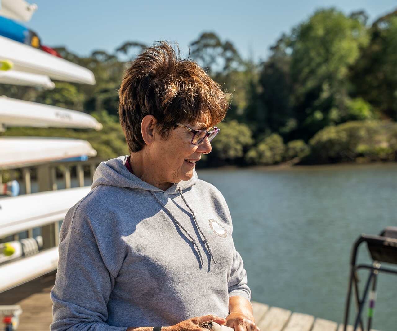 A side profile of a smiling woman standing at the shore.