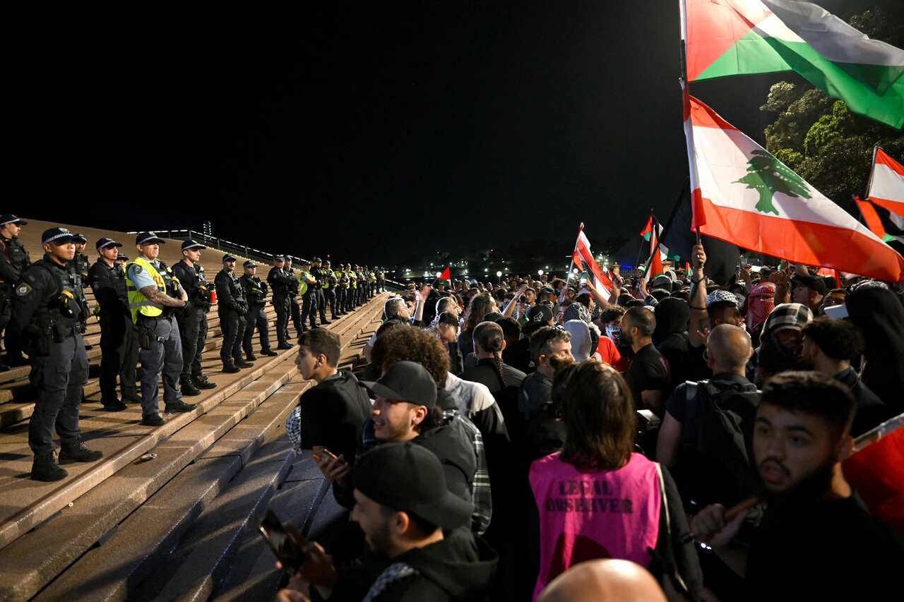 Police stand on the steps of the Sydney Opera House looking out at protesters.