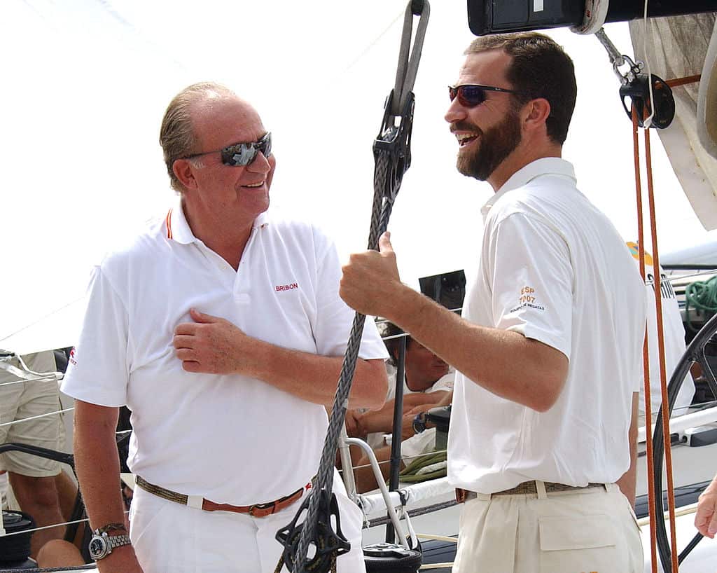 Two men wearing white polo shirts standing facing each other on a yacht