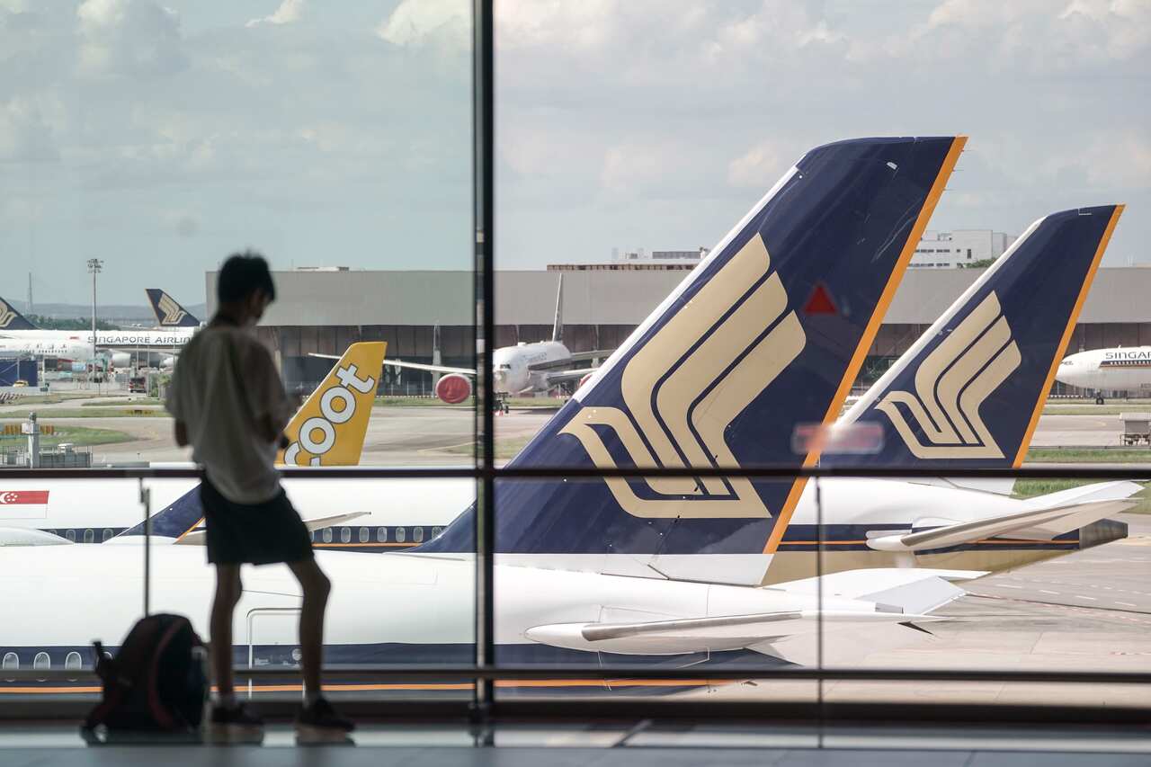 A boy is silhouetted against the tailplanes of Singapore Airlines commercial jets at the Changi Airport