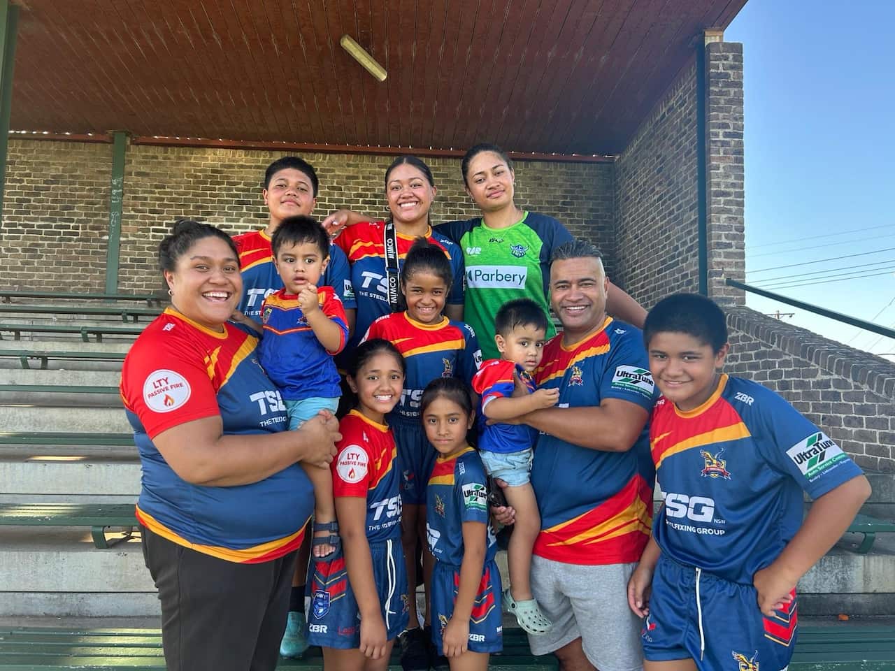 A large family wearing football stripes smile at the camera.