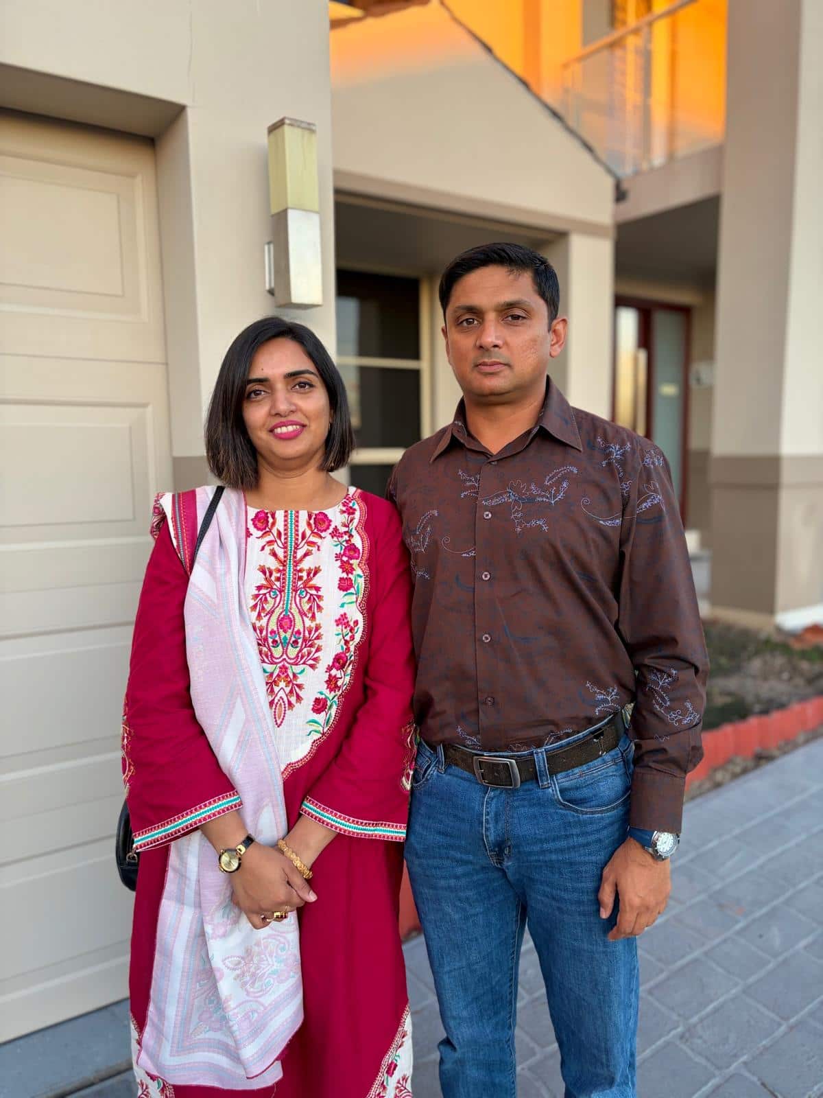 a man and a woman standing in front of a house 