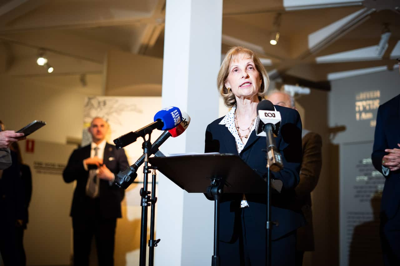 A woman in a suit speaking into a microphone at a press conference