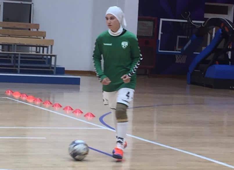 Mursal plays football on an indoor wooden court 